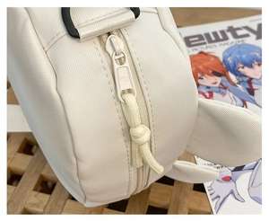 Detailed close-up of zipper and seam quality on white canvas cartoon bear crossbody bag