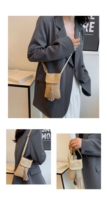 Détail de la texture en paille tressée et du pompon décoratif sur le sac pour téléphone