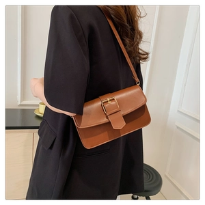 Close-up of brown vintage leather underarm bag with gold buckle on a model's shoulder