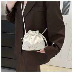 Détail de la broderie florale sur le sac seau blanc cassé avec cordon de serrage