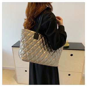 Détail d'un sac cabas matelassé doré avec bandoulière noire porté par un mannequin