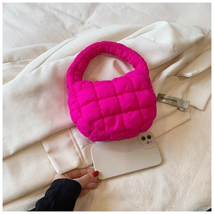 Macro detail of magenta quilted puffer handbag with soft padded texture and top handle