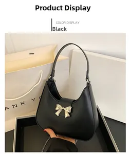 Detail view of black hobo bag with gold metal bow clasp and smooth leather finish