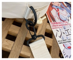 Detailed close-up of a white canvas bag showing the durable black strap hook and zipper
