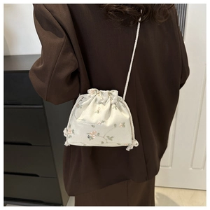 Vue détaillée du sac bourse crème avec cordon de serrage et broderies florales