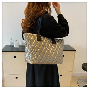 Grand sac cabas matelassé argenté avec bandoulières noires porté par un mannequin