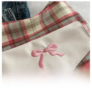 Detail aus rosa-grünem Karostoff mit weißem Lederpatch und rosa Schleifenstickerei auf Tasche