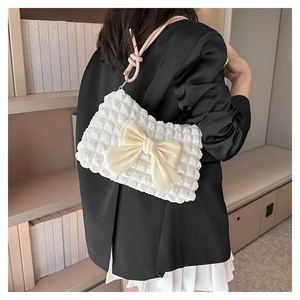 Detail der weißen Smocking-Achseltasche mit Seidenschleife und rosa Schultergurt