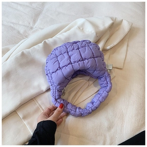 Detail shot of purple quilted puffy cloud bag with textured fabric and top zipper