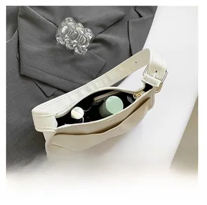 Top-down view of spacious white crescent bag interior with daily items and cosmetics