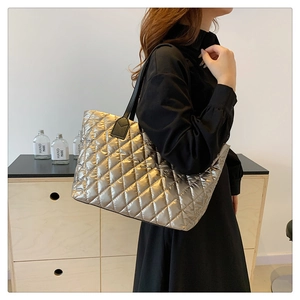 Détail du grand sac cabas matelassé doré champagne avec bandoulières noires sur un mannequin