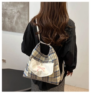 Detail des karierten Rucksacks mit rosa Schleifenstickerei und Schultergurten