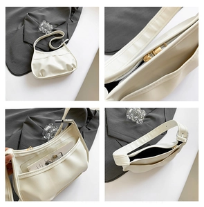 Detail of white pleated crescent bag featuring golden metal zipper and smooth PU leather