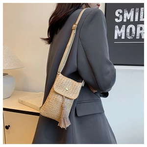 Détail du sac bandoulière en paille tressée avec boucle verte et longues franges