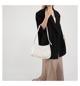 Detail of off-white pleated crescent hobo bag with sleek shoulder strap on model