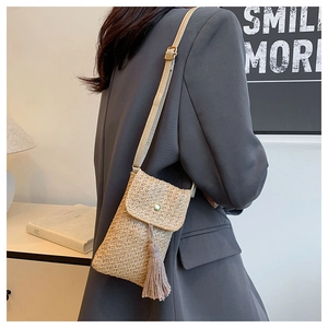 Détail sac de téléphone en paille tissée avec glands et fermoir perle vert clair bandoulière