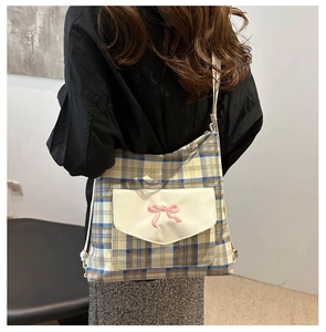 Detail der karierten Canvas-Tasche mit rosa Schleifenstickerei und Ledertasche