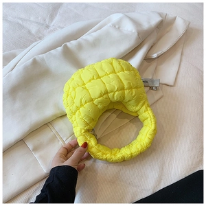 Detail of a bright yellow quilted cloud bag featuring a puffy texture and zipper closure