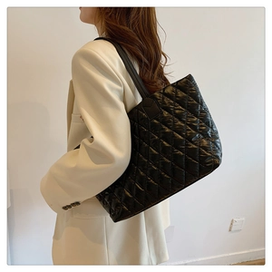 Détail d'un sac cabas noir matelassé avec finition brillante et fines bandoulières chic