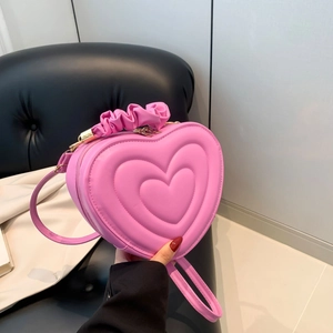 Detailed close-up of heart-shaped quilted leather handbag with ruffled handle