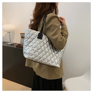 Grand sac fourre-tout argenté matelassé avec lanières noires porté par un mannequin