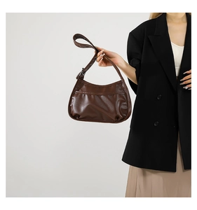 Detailed view of a brown crescent shoulder bag with stitching pocket worn by a model
