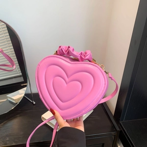 Pink heart-shaped bag featuring unique scrunchie handle and quilted surface detail
