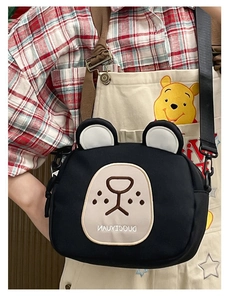 Detail view of the black cartoon bear canvas bag with adjustable nylon strap on a model