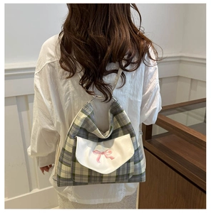 Nahaufnahme eines karierten Rucksacks mit Schleifenstickerei und cremefarbenen Riemen