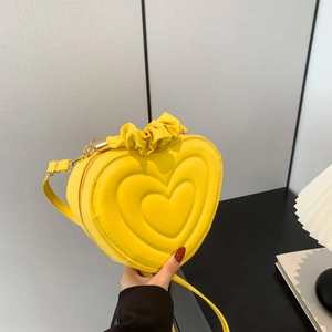 Detail view of bright yellow heart-shaped bag with scrunchie handle and gold zipper