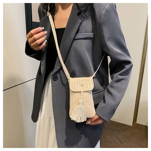 Gros plan détaillé du sac de téléphone en paille tressée avec franges et bouton métal
