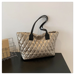 Détail du sac cabas matelassé or champagne avec poignées en cuir noir et surpiqûres