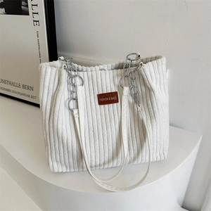 Detail of white corduroy tote bag with silver chain strap and leather fashion label