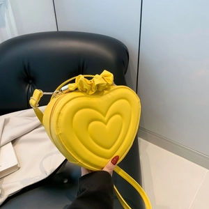 Macro shot of bright yellow heart shaped PU leather bag with embossed heart pattern detail