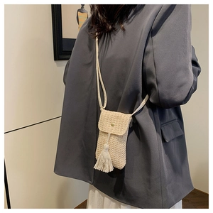 Détail du sac de téléphone tissé beige avec bouton doré et longues franges de style bohème