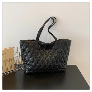 Détail du sac fourre-tout en nylon noir matelassé avec finition brillante et surpiqûres