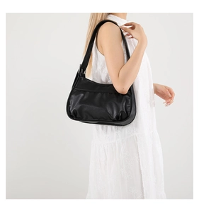 Side view of a black pleated crescent bag with adjustable wide strap on model