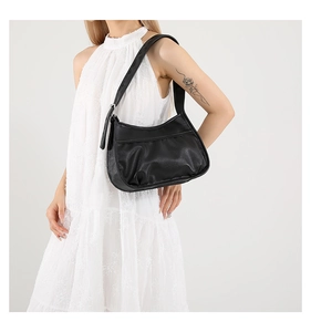 Detail of black pleated shoulder bag with metal buckle on white summer dress