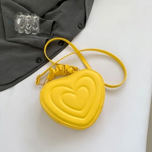 Detail of heart-shaped embossed yellow crossbody bag with ruffled handle and 3D layers