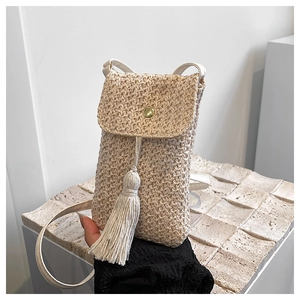 Détail du sac de téléphone en paille tressée avec pompon et boucle dorée ronde