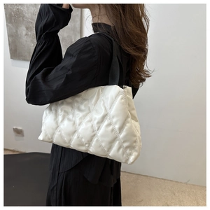 Gros plan d'un sac seau blanc matelassé avec surpiqûres losanges et large bandoulière noire