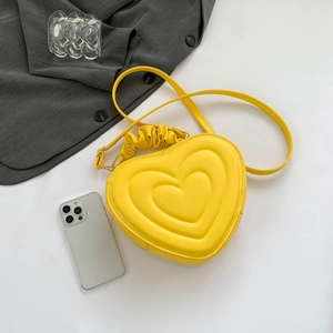 Detail of yellow heart-shaped bag with quilted texture, scrunchie handle and gold hardware