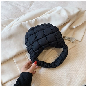 Close-up of black quilted cloud bag texture and fluffy soft fabric on white blazer