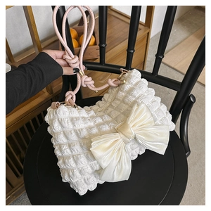 Detail einer weißen Faltenhandtasche mit großer Satinschleife und rosa Kordelgriff