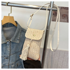Détail de la pochette de téléphone en paille tressée avec pompon et fermeture à bouton métal