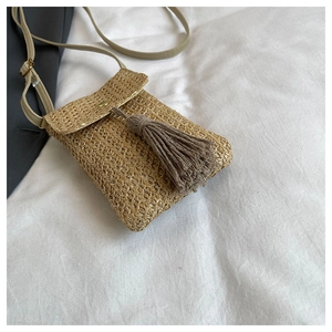 Détail de la pochette téléphone en paille tressée beige avec pompon et bandoulière fine