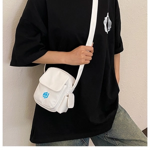 Detailansicht der weißen Canvas-Umhängetasche mit blauem Logo und breitem Gurt