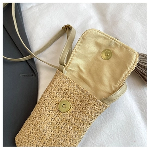 Détail du sac de téléphone en paille avec fermoir magnétique, doublure et pompon déco