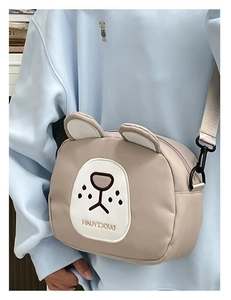 Detail of cute cartoon dog embroidery and adjustable strap on a beige crossbody bag