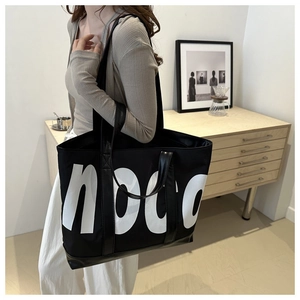 Dettaglio della borsa tote in tela nera con scritta noco bianca e manico in similpelle